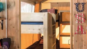 A wooden interior with bunk beds, a desk with a chair, and a wall-mounted American flag. - Accessible, Glamping Tent in Bar Harbor,Just 4 miles from Acadia National Park (Bar Harbor)