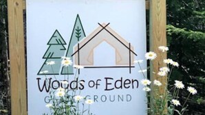 A sign for 'Woods of Eden Campground' with a wooden structure and a planter with flowers. - Accessible, Glamping Tent in Bar Harbor,Just 4 miles from Acadia National Park (Bar Harbor)