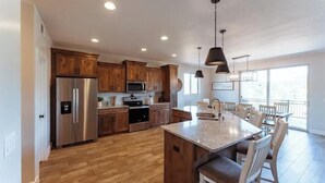 A modern kitchen with wooden cabinets, stainless steel appliances, and a large island with seating. - Zion views- R Family Square + Resort Access (Orderville)