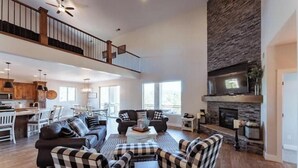 A spacious living area with a high ceiling, a fireplace, and a dining area with a kitchen in the background. - Zion views- R Family Square + Resort Access (Orderville)