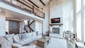 Un salon spacieux avec un haut plafond, une cheminée, un escalier et un balcon.