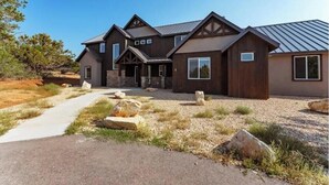 Une maison moderne à deux étages, dotée de fondations en pierre, de grandes fenêtres et d’une allée gravillonnée.