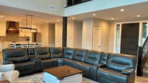 A modern living room with a sectional sofa, a coffee table, and a kitchen in the background. - Peace at Zion + Zion Views + Resort Access (Orderville)