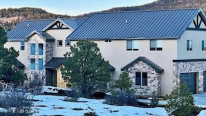 A modern two-story house with a stone facade, a metal roof, and a driveway leading to a garage. - Peace at Zion + Zion Views + Resort Access (Orderville)