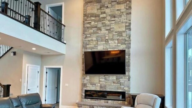 A spacious living room with a stone fireplace, leather sofas, and a large TV. - Peace at Zion + Zion Views + Resort Access (Orderville)
