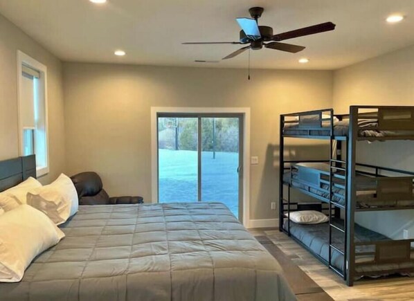 A bedroom with a bed, a ceiling fan, a bunk bed, and a sliding glass door leading to a patio.