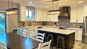 A modern kitchen with white cabinetry, a central island, and pendant lighting. - Peace at Zion + Zion Views + Resort Access (Orderville)