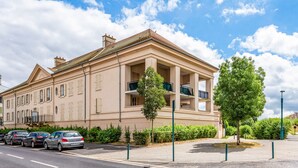 A large, beige building with multiple balconies and a parking lot in front. - Apartment Les Alizés  (Bailly-Romainvilliers)