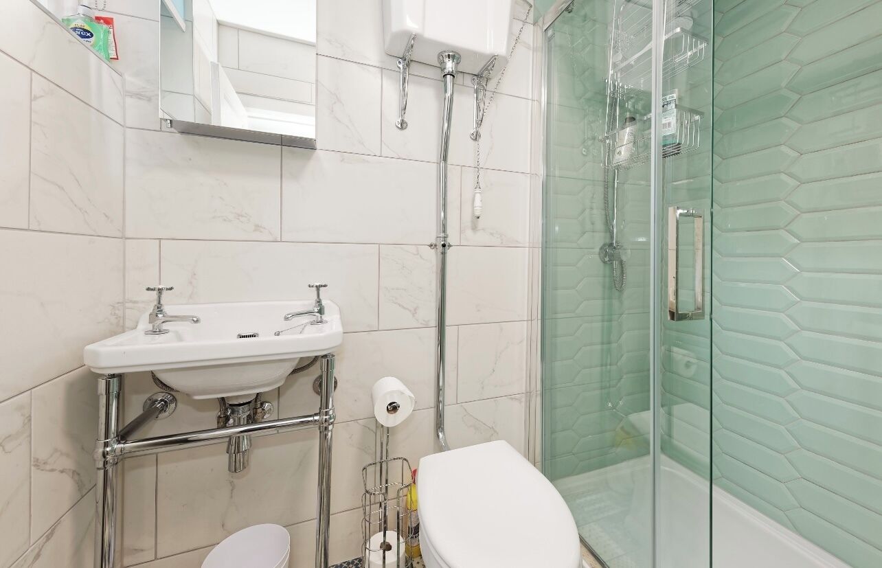 A bathroom with a glass-enclosed shower, a white sink, and a toilet.