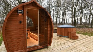 A wooden cabin with a curved roof, an open door revealing a bench and a small table inside, and a hot tub outside. - Beautiful home in Brørup with WiFi (Brørup)