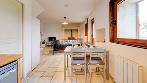 Une cuisine moderne avec des meubles blancs, un lave-vaisselle et un coin repas comprenant une table et des chaises.