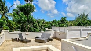 Una terraza en la azotea con sillones de descanso, una pequeña mesa y una zona de piscina.