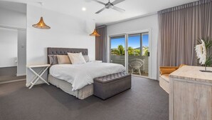 Ein modernes Schlafzimmer mit einem großen Bett, einem Schreibtisch und einem Balkon mit Blick.