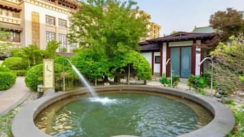 A courtyard with a circular fountain, surrounded by well-maintained greenery and traditional architecture.