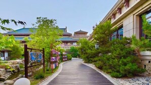 A pathway leading to a traditional building with a tiled roof, surrounded by greenery and a wooden fence. - Evergrande Hotel，Tianjin Dongli Lake (Tianjin)