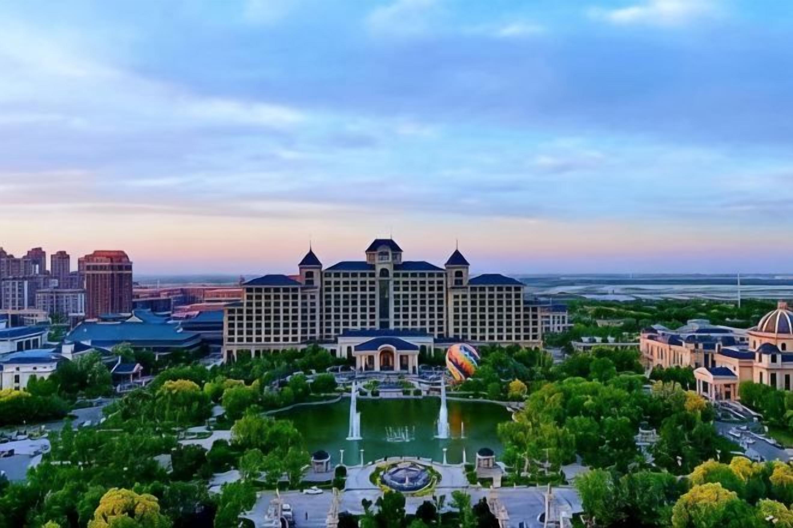 A large hotel with a central courtyard, multiple fountains, and surrounding greenery.