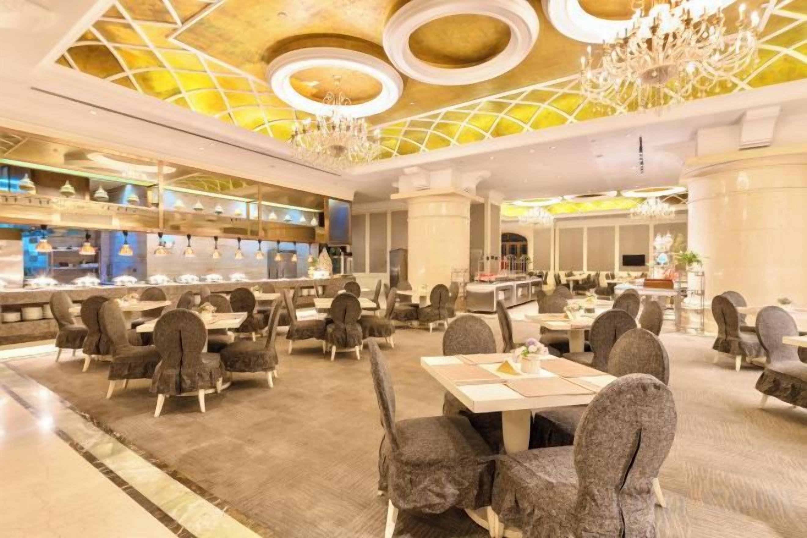 A spacious dining area with multiple tables and chairs, a bar area with a counter, and a chandelier.
