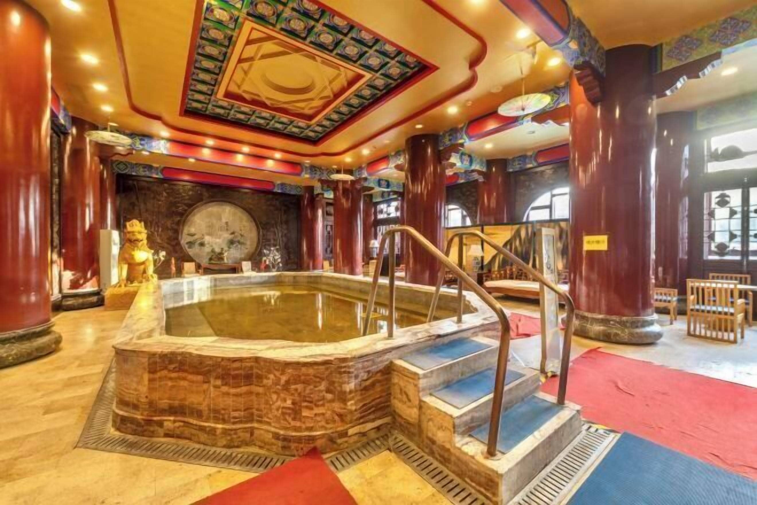 A hot tub with a stone base, surrounded by wooden columns and a colorful ceiling.