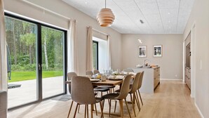A modern dining area with a large table, chairs, and a view of the outdoors.
