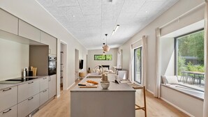 A modern kitchen with a central island, a dining area with a view, and a large window.