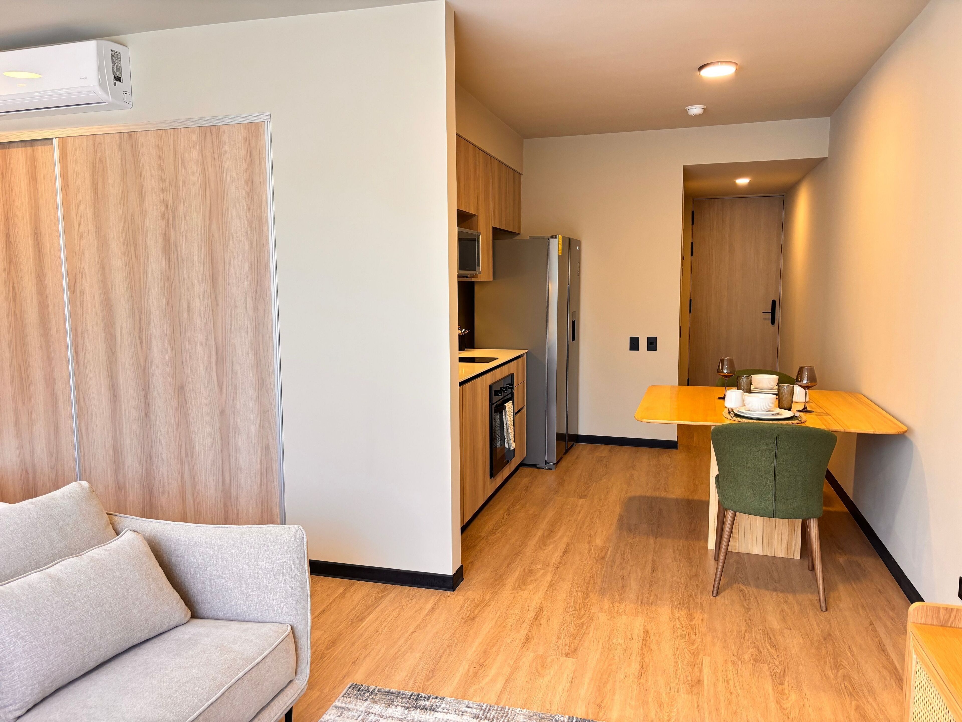 A modern apartment with a living room, kitchenette, and dining area.