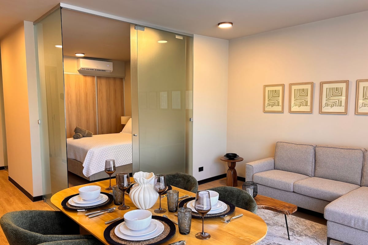 A modern hotel room with a dining area, a sofa, and a bed.
