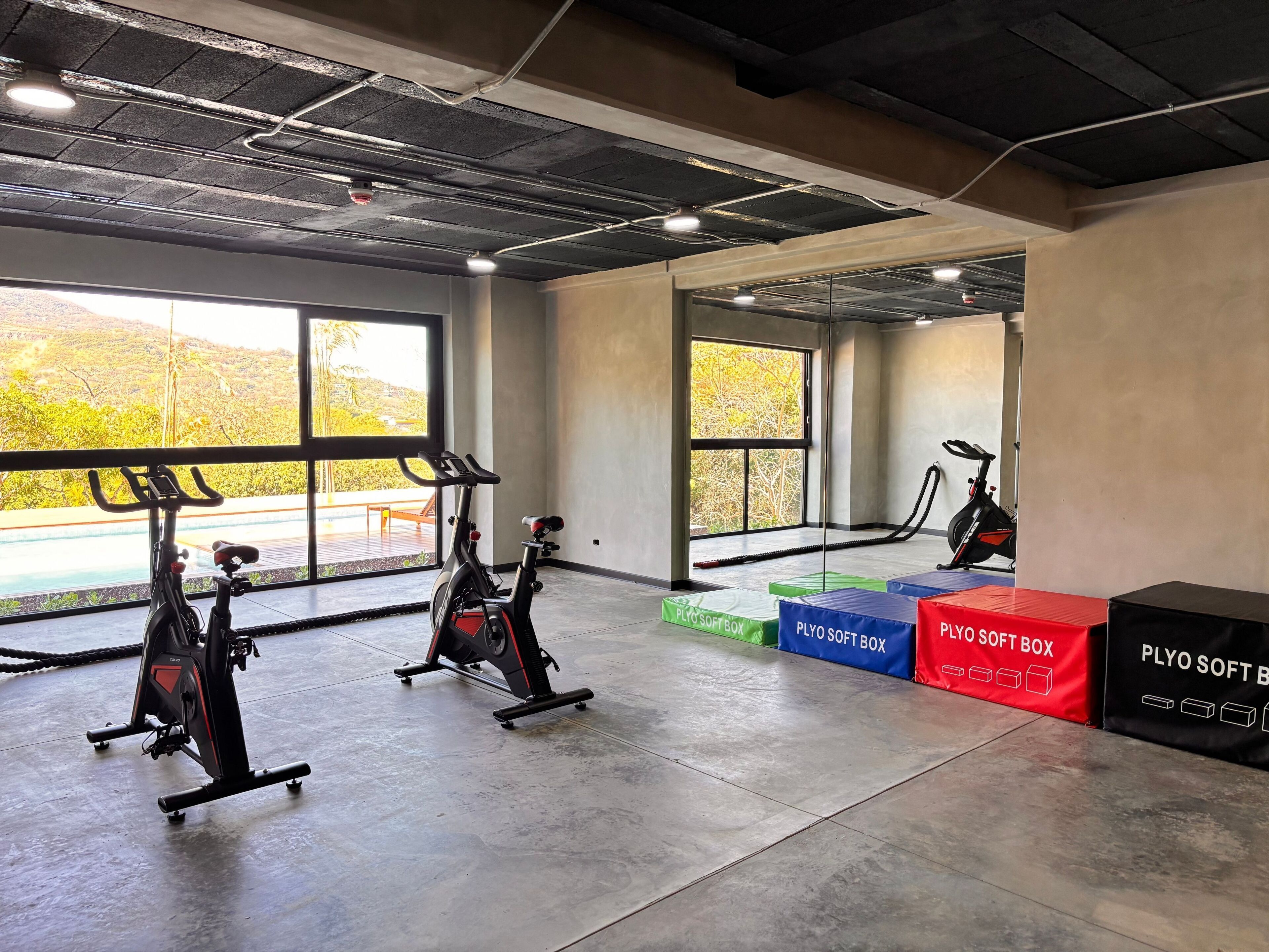 A gym with stationary bikes, large windows, and exercise equipment.