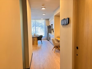 Una cocina moderna con comedor, piso de madera y un amplio ventanal con persianas.