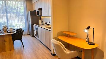 A modern kitchen with a dining area, a small table with a lamp, and a chair.