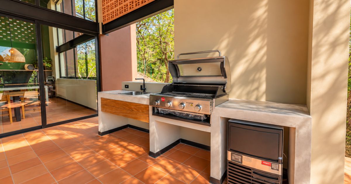 An outdoor kitchen area with a grill, a built-in oven, and a countertop.