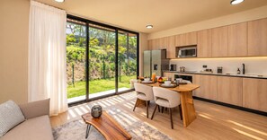 Una cocina moderna con comedor, ventanas amplias y vista a un jardín.