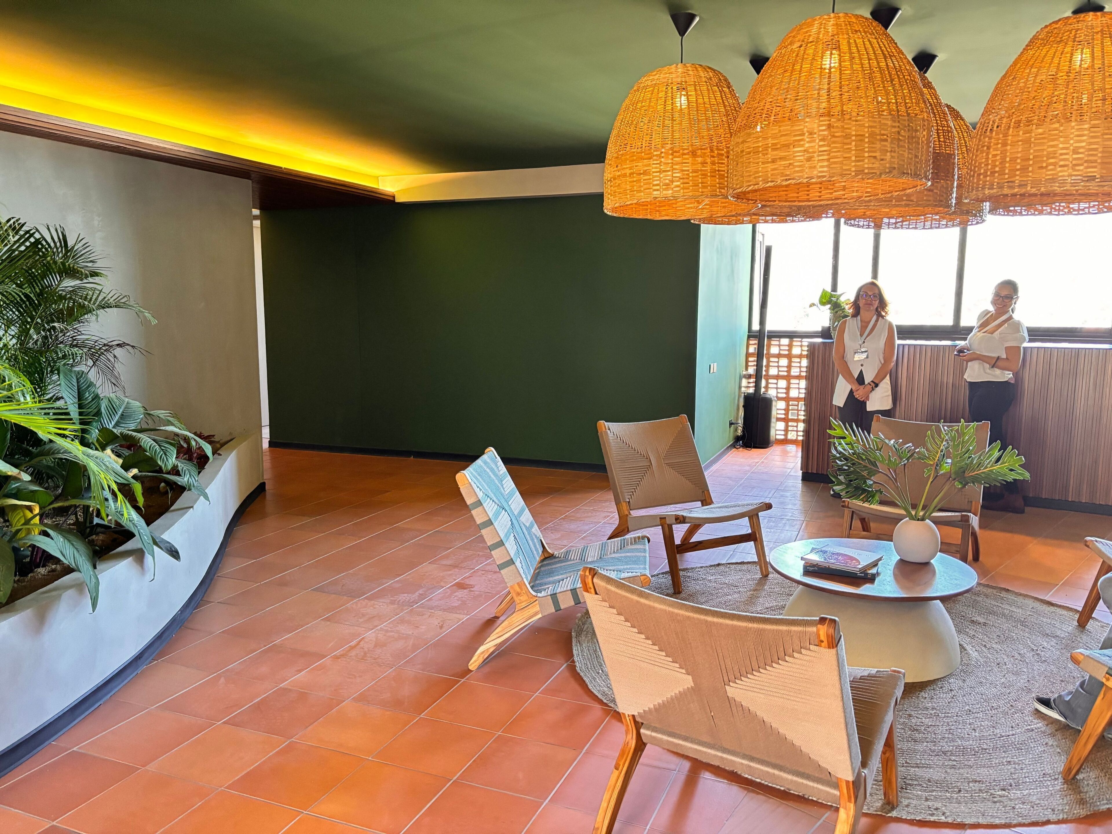 A spacious lounge area with wicker pendant lighting, a round coffee table, and a seating arrangement including a sofa and chairs.