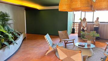 A spacious lounge area with wicker pendant lighting, a round coffee table, and a seating arrangement including a sofa and chairs.