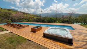 A wooden deck with a hot tub, lounge chairs, and a rectangular planter. - BEE Suites San José - Santa Ana (Santa Ana)