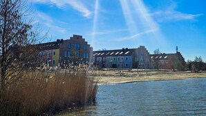 Une propriété située au bord de l’eau, comprenant plusieurs bâtiments, avec un ciel dégagé et un plan d’eau.