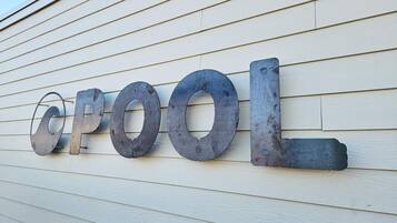 A metal sign with the letters "CPOOL" mounted on a wooden wall.