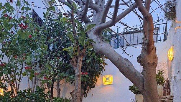 Un sendero de piedra que lleva a una pared blanca con un letrero cuadrado amarillo.