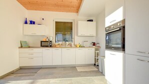 Une cuisine moderne avec des armoires blanches, un four encastré et un plafond en bois.