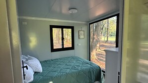 Een slaapkamer met een bed, een raam en een deur.