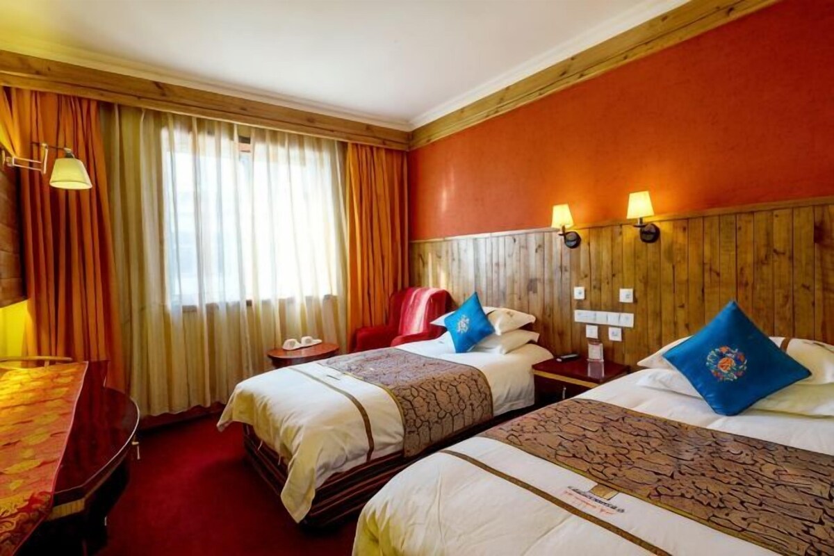 Une chambre d’hôtel avec deux lits, un bureau et une chaise.