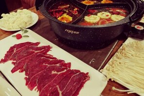 A dining table with a hot pot, sliced meat, and vegetables. - Da Zang Sunlight Hotel (Zoige)