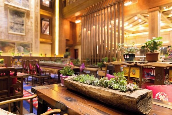 A wooden interior with a long table, chairs, and potted plants.