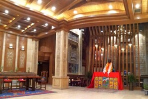 A lobby with a grand wooden ceiling, a piano, and a red table with a colorful cloth. - Da Zang Sunlight Hotel (Zoige)