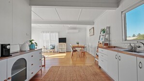 A modern kitchen with white cabinetry, wooden countertops, and a dining area with a table and chairs.