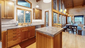 A spacious kitchen with wooden cabinets, a large island, and ample natural light from the windows. - Cozy Home•Hot Tub•Sauna•EV Charger•Bay & Dining 5m (Bay City)
