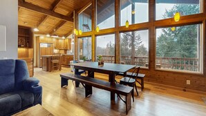 A spacious wooden interior with a large dining table, benches, and a blue sofa. - Cozy Home•Hot Tub•Sauna•EV Charger•Bay & Dining 5m (Bay City)