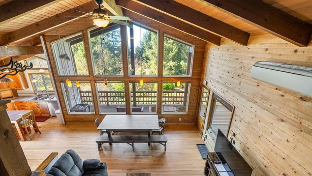 A spacious cabin with a large dining table, a sofa, and a kitchen area. - Cozy Home•Hot Tub•Sauna•EV Charger•Bay & Dining 5m (Bay City)