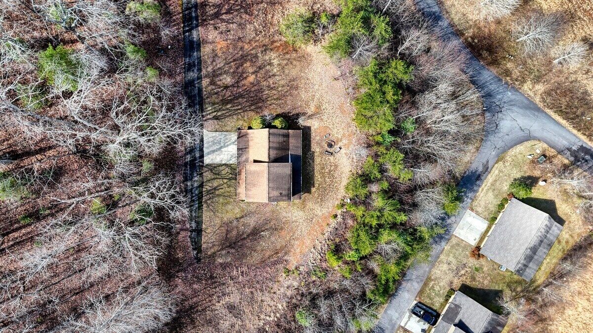Luchtbeeld van een huis omringd door bomen en een weg.