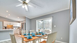 A dining area with a wooden table set for four, surrounded by white chairs. A ceiling fan is visible above the table. - 8 Mi to Jordan Lake: Spacious New Hill Home (New Hill)