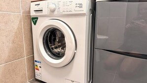 Una lavadora de carga frontal con panel de control, dispensador de detergente y etiqueta que indica eficiencia energética.